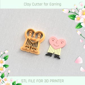 May include: Two 3D printed clay cutters for earrings. One cutter is shaped like a heart with a smiling face and the other is shaped like two people holding hands with a smiling face. The cutters are made for a 3D printer and are labelled "STL FILE FOR 3D PRINTER".