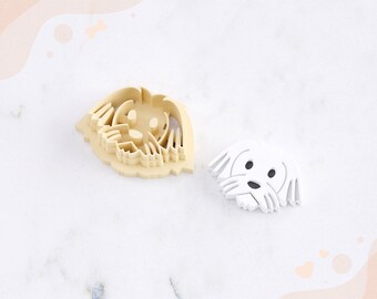 May include: A white clay cutter for earrings in the shape of a dog's head. The cutter is on a white marble surface. STL FILE FOR 3D PRINTER.