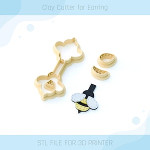 Puede incluir: Un cortador de arcilla impreso en 3D para pendientes con forma de abeja. El cortador está hecho de plástico beige y tiene un diseño detallado. La abeja tiene detalles en negro, amarillo y blanco. El texto "STL FILE FOR 3D PRINTER" está impreso debajo de la imagen.