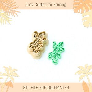 May include: Two clay cutters for earrings. One is a beige cutter in the shape of a lizard, and the other is a green lizard-shaped earring. The text "Clay Cutter for Earring" and "STL FILE FOR 3D PRINTER" are at the top and bottom of the image.