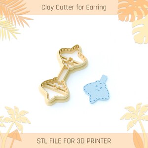 May include: A beige clay cutter for earrings and a light blue earring cutout. The cutter is in the shape of a bow tie with a connecting bar. The cutout is a stingray shape with a smiling face. Text reads "Clay Cutter for Earring" and "STL FILE FOR 3D PRINTER."