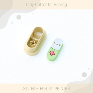 May include: A beige clay cutter for earrings and a green and white pill-shaped earring. The pill-shaped earring has a red cross design and a cute face. The text "Clay Cutter for Earring" and "STL FILE FOR 3D PRINTER" are visible.
