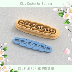 Puede incluir: Un cortador de arcilla beige para pendientes y un recorte de pendiente azul claro, ambos con un diseño de eslabones de cadena. El texto "Clay Cutter for Earring" y "STL FILE FOR 3D PRINTER" son visibles. Elementos florales decorativos en el fondo.