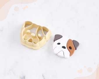 May include: A 3D printed clay cutter for earrings in the shape of a dog's face. The cutter is beige and the sample earring is white with brown accents. The text "STL FILE FOR 3D PRINTER" is at the bottom of the image.