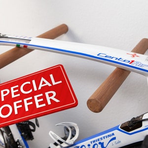 Könnte beinhalten: Weiß-blaues Rennrad mit Holz-Wandhalterung. Das Fahrrad hat den Text "Cento1Air" und "Triestina" auf dem Rahmen. Ein rotes Etikett mit "SPECIAL OFFER" ist im Vordergrund.