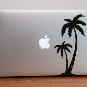 May include: A silver laptop computer with a black palm tree silhouette sticker on the back. The sticker features two palm trees with a small island at the base.