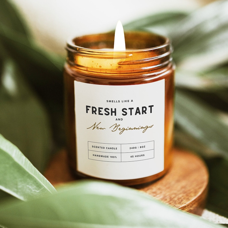 A candle in a brown glass jar with a white label