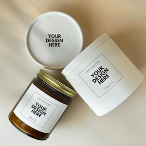 Könnte beinhalten: Draufsicht auf drei Kerzenbehälter: ein Glas mit goldenem Deckel und zwei weiße Zylinder. Jeder hat ein Etikett mit "YOUR DESIGN HERE" und "HAND-POURED CANDLE". Die Kerzen sind 240 Gramm / 8 oz.