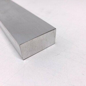 Puede incluir: Una barra rectangular de aluminio plateada con acabado cepillado.