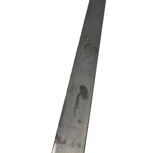 May include: A long, rectangular metal bar with a slightly textured surface. The bar is a dull gray color and appears to be made of steel or a similar metal. The edges are straight and the overall shape is simple.