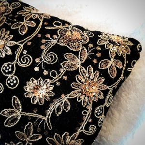 May include: Black velvet cushion with gold and brown floral embroidery and sequins.