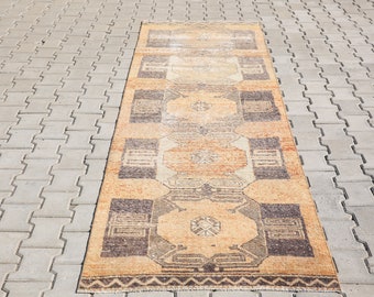 Può includere: Un tappeto rettangolare lungo con un motivo geometrico in tonalità di marrone, beige e arancio. Il tappeto ha un bordo a frangia.