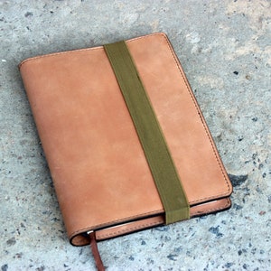 May include: A brown leather notebook with a green elastic band closure.