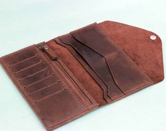 May include: A brown leather wallet with multiple card slots and a zippered compartment. The wallet is open to reveal the interior.