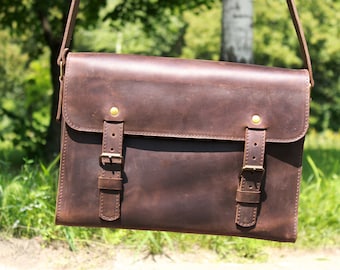 May include: A brown leather messenger bag with two adjustable buckles and brass accents. The bag has a flap closure and a long strap.