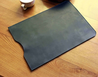 May include: A dark blue leather laptop sleeve with a flap closure and stitched edges.