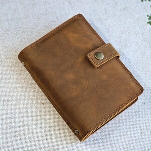 May include: A brown leather wallet with a flap closure and a single snap button. The wallet has a worn, distressed look.