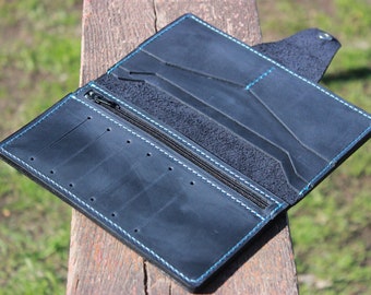 May include: A black leather wallet with a zipper closure and blue stitching. The wallet has multiple card slots and a billfold.