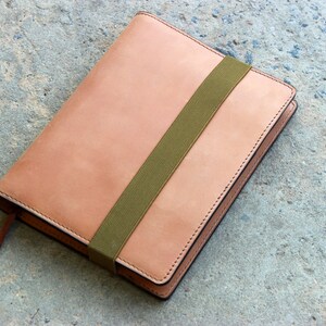May include: A tan leather notebook with a green elastic band closure.