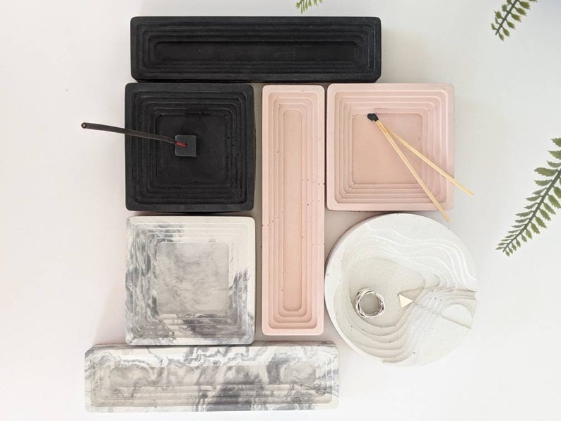 May include: Set of six concrete trays in various shapes and sizes. The trays are in black, white, and pink with a marbled pattern. The trays are ideal for organising small items, such as jewellery, keys, or incense.