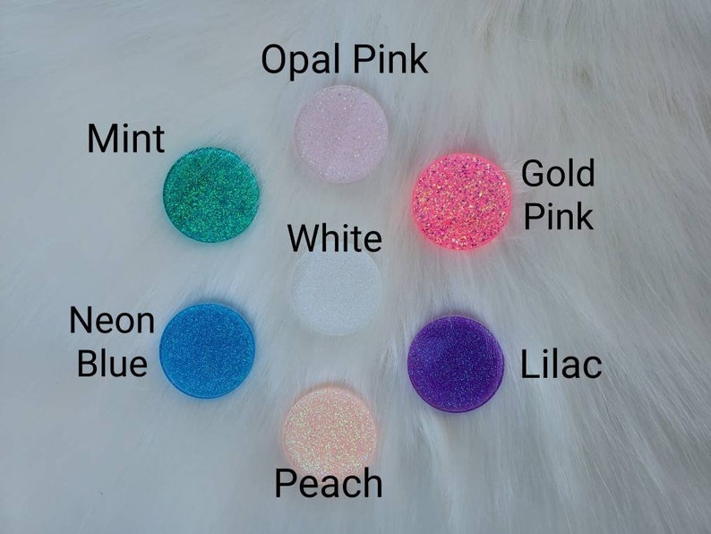May include: Assortment of 10 round phone grips with glitter embedded in the resin. Colors include: opal pink, mint, white, gold pink, neon blue, lilac, and peach.