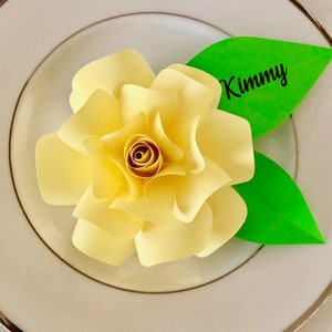 May include: A yellow paper flower with green paper leaves and the name "Kimmy" written on one of the leaves.