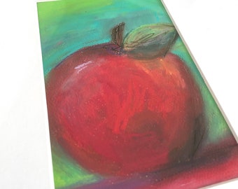 May include: A framed pastel drawing of a red apple with a green leaf on a teal, purple, and pink background.