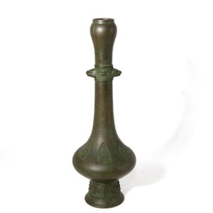 May include: A tall, green bronze vase with a bulbous body and a narrow neck. The vase has intricate carvings and a decorative base.