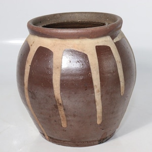 以下が含まれることがあります： 白く釉薬がかかった茶色の陶器の壺。壺は丸みを帯びた形をしていて、開口部が広い。