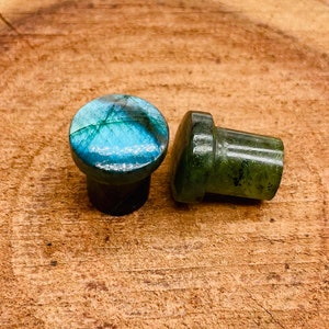 May include: Two round, green and blue gemstone bottle stoppers. The stoppers are made of polished stone and have a smooth, rounded surface.