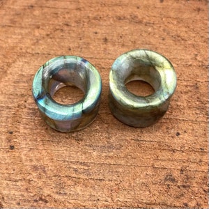 Puede incluir: Un par de expansores de oreja de piedra de labradorita verde y dorada iridiscente. Los expansores son redondos y tienen un acabado liso y pulido.