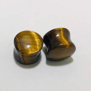 May include: Pair of tiger's eye stone ear gauges, one is a simple round shape and the other is a flared shape.