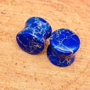 May include: Two blue and gold marbled stone ear gauges. The gauges are round and have a smooth, polished finish.