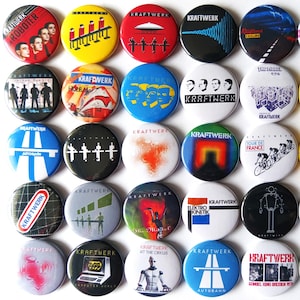 May include: A collection of 25 round Kraftwerk band badges. The badges feature various album covers and logos. The badges are colourful and have a glossy finish.