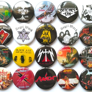 Puede incluir: Una colección de 16 botones redondos de metal con cierre de pin, que muestran varios logotipos y portadas de álbumes de bandas de heavy metal. Los botones son negros, blancos, rojos, amarillos y verdes con imágenes de nombres de bandas, títulos de álbumes y miembros de bandas.