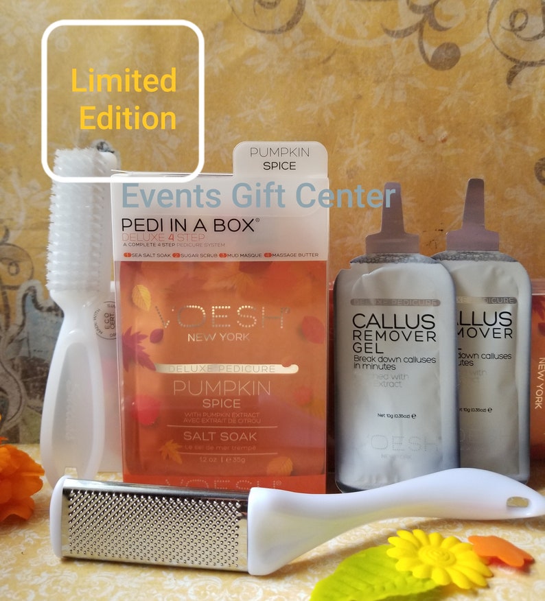May include: A limited edition pumpkin spice pedicure kit with a foot brush, foot file, and two packets of callus remover gel. The kit is packaged in a box with the text "PEDI IN A BOX" and "DELUXE 4 STEP" on the front. The box is decorated with fall leaves and the text "PUMPKIN SPICE" in a white font.