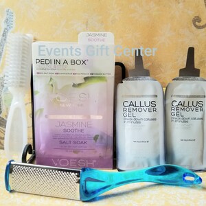 May include: A purple and white box with the text "PEDI IN A BOX" and "JASMINE SOOTHE" on it. The box contains a foot care kit with sea salt soak, sugar scrub, mud masque, and massage butter. Two clear tubes of callus remover gel are also shown. The tubes are labeled "CALLUS REMOVER GEL" and have a net weight of 10g (0.35oz).