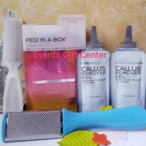 May include: A set of foot care products in a gift box. The box contains a foot scrub, a foot mask, a foot file, and two packets of callus remover gel. The products are all labeled with the brand name "Voesh" and the scent "Coco Colada Oasis".