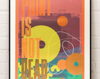 May include: A colorful poster with the text "PRINT IS NOT DEAD" in bold, orange letters. The background is a vibrant orange with a pattern of small circles. There are overlapping circles in yellow, orange, and green.