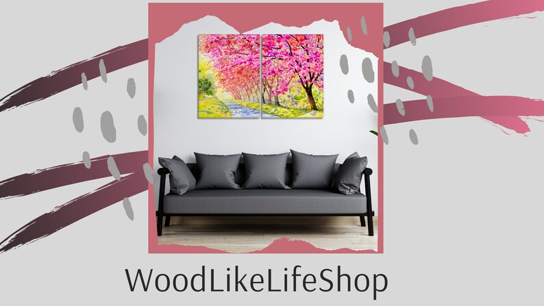May include: A split canvas print of a watercolor painting depicting a path lined with pink cherry blossom trees. The print is hanging on a white wall above a gray sofa.