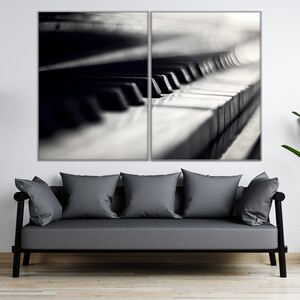May include: A black and white photograph of a piano keyboard, split into two sections. The image is displayed in a living room setting with a gray sofa, a floor lamp, and a potted plant.