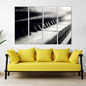 May include: A black and white photo of a piano keyboard, split into four sections, with a blurred effect. The photo is displayed on a wall above a yellow couch.