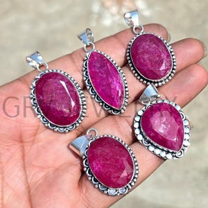 Può includere: Cinque ciondoli d'argento con pietre preziose di rubino rosa. I ciondoli sono di varie forme, tra cui ovale, a goccia e a pera. I ciondoli sono incastonati in argento e hanno dettagli intricati.