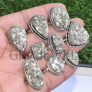 Puede incluir: Una colección de diez anillos de plata con engastes de piedras preciosas de pirita. Los anillos son de varias formas y tamaños, incluyendo ovalados, cuadrados y en forma de lágrima. Las piedras preciosas de pirita son de color gris claro con un acabado brillante.