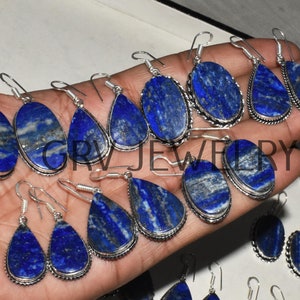 Puede incluir: Una colección de pendientes de plata con gotas de lapislázuli azul. Los pendientes tienen forma de lágrima y tienen un diseño de alambre de plata alrededor de los bordes.