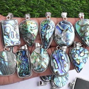 Könnte beinhalten: Sortiment an Abalone-Muschel-Anhängern mit silbernen Einstellungen. Die Anhänger sind in verschiedenen Formen, darunter oval, tropfenförmig und rechteckig. Die Abalone-Muschel hat einen wunderschönen irisierenden Glanz in Blautönen, Grüntönen und Violett.