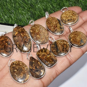 Puede incluir: Una colección de nueve colgantes de plata con inserciones de piedras preciosas marrones y doradas. Los colgantes son de varias formas, incluyendo ovaladas, redondas y de lágrima.