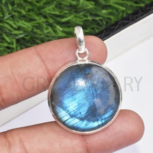 May include: A round silver pendant with a blue labradorite gemstone. The pendant has a smooth, polished surface and a silver bail.