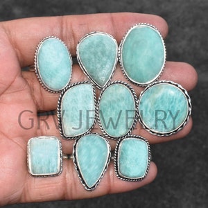 May include: Ten silver rings with light green gemstones. The rings have a decorative, twisted wire design around the edges of the stones.