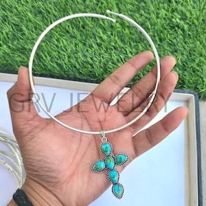 May include: A silver choker necklace with a turquoise cross pendant. The cross is made of silver and has five turquoise stones set in it.
